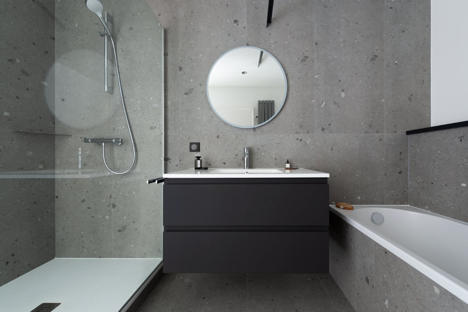 Salle de bain minimaliste grise avec baignoire et paroi de douche, design épuré par architecte d'intérieur Metz.