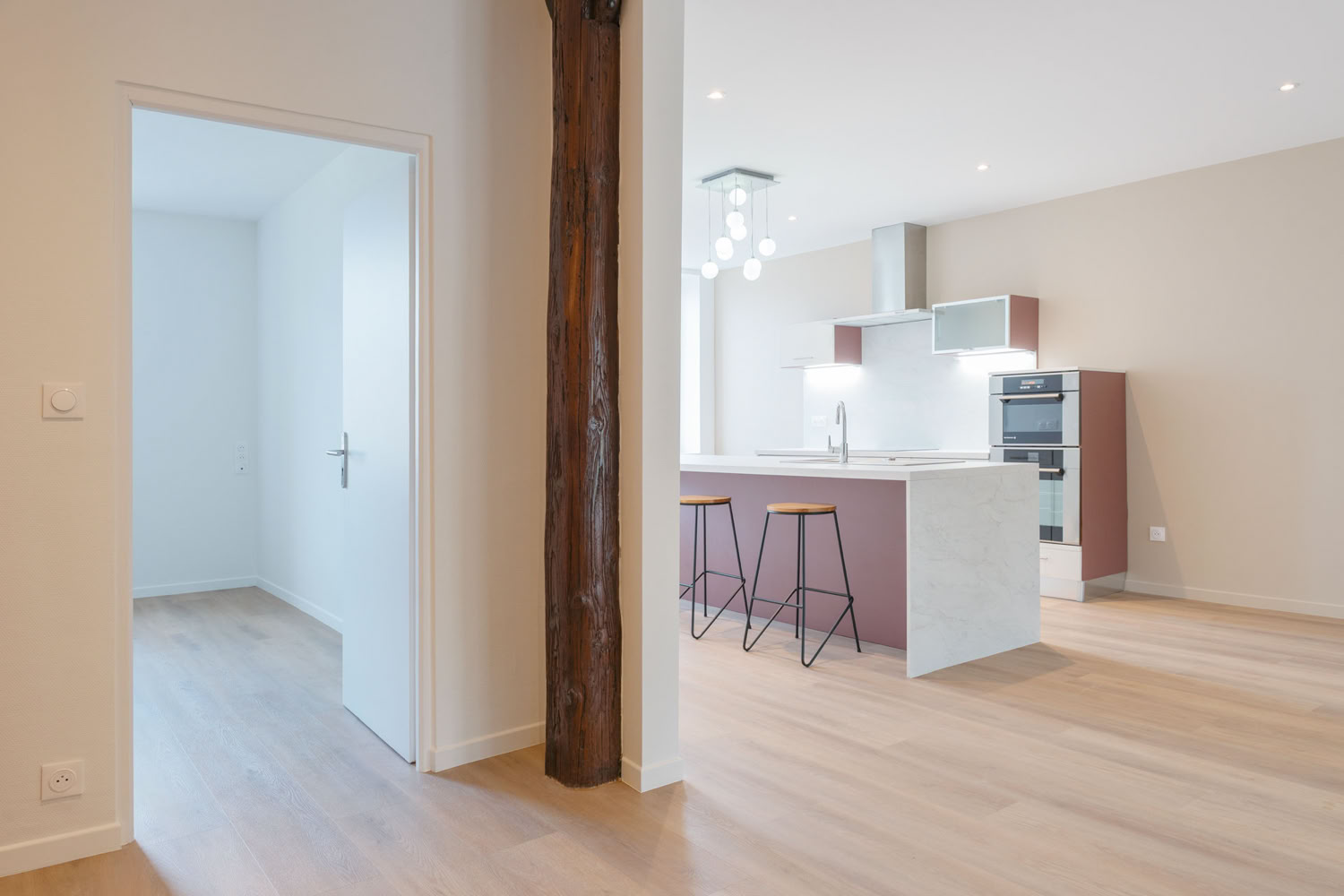 Vue d'ensemble d'une cuisine contemporaine blanche avec îlot, projet de rénovation à Metz.