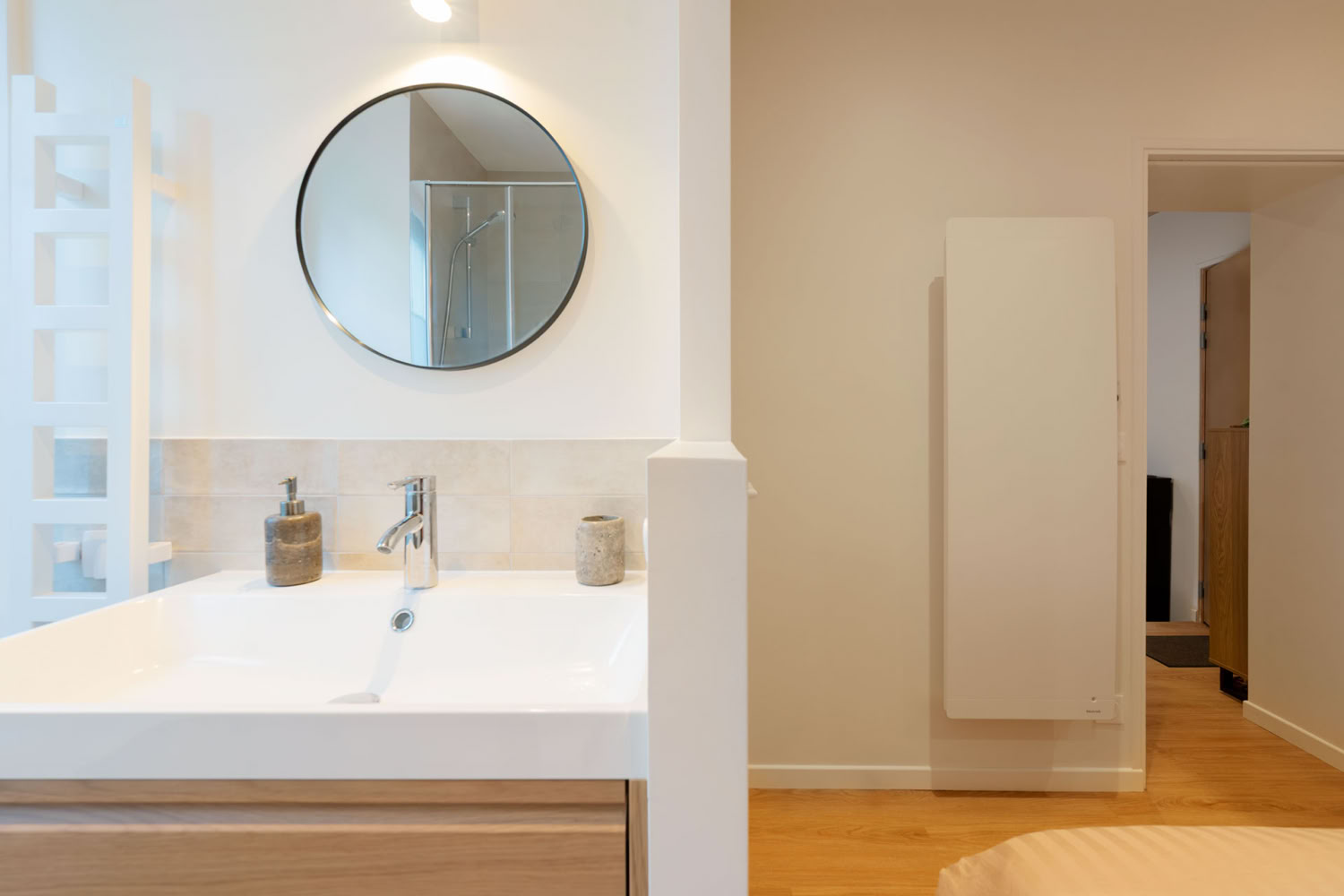 Vue d'ensemble de la salle de douche rénovée avec radiateur sèche-serviette et rangements intégrés.