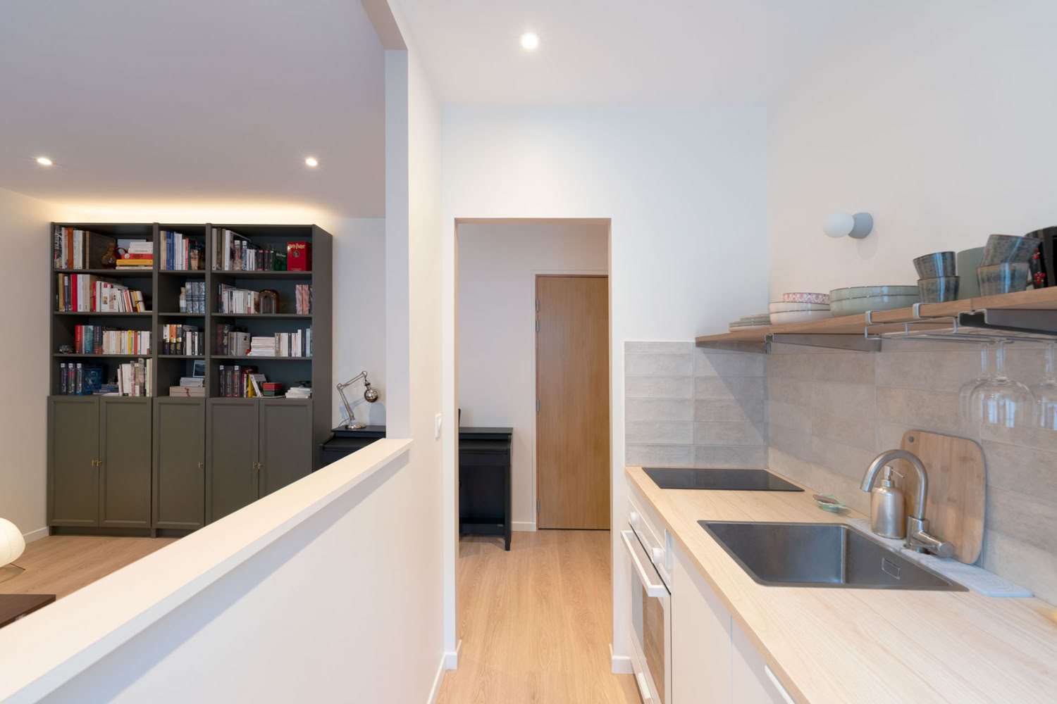 Vue depuis la cuisine vers le séjour montrant la circulation fluide et la paroi semi-ouverte.