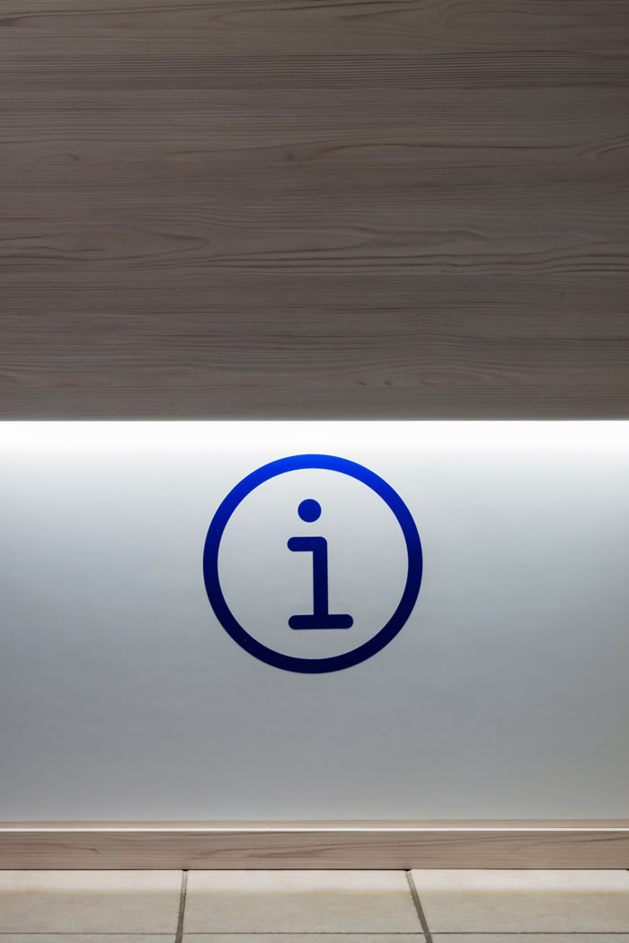 Détail signalétique lumineuse "Information" sur comptoir en bois, aménagement de bureaux administratifs en Moselle Est. 