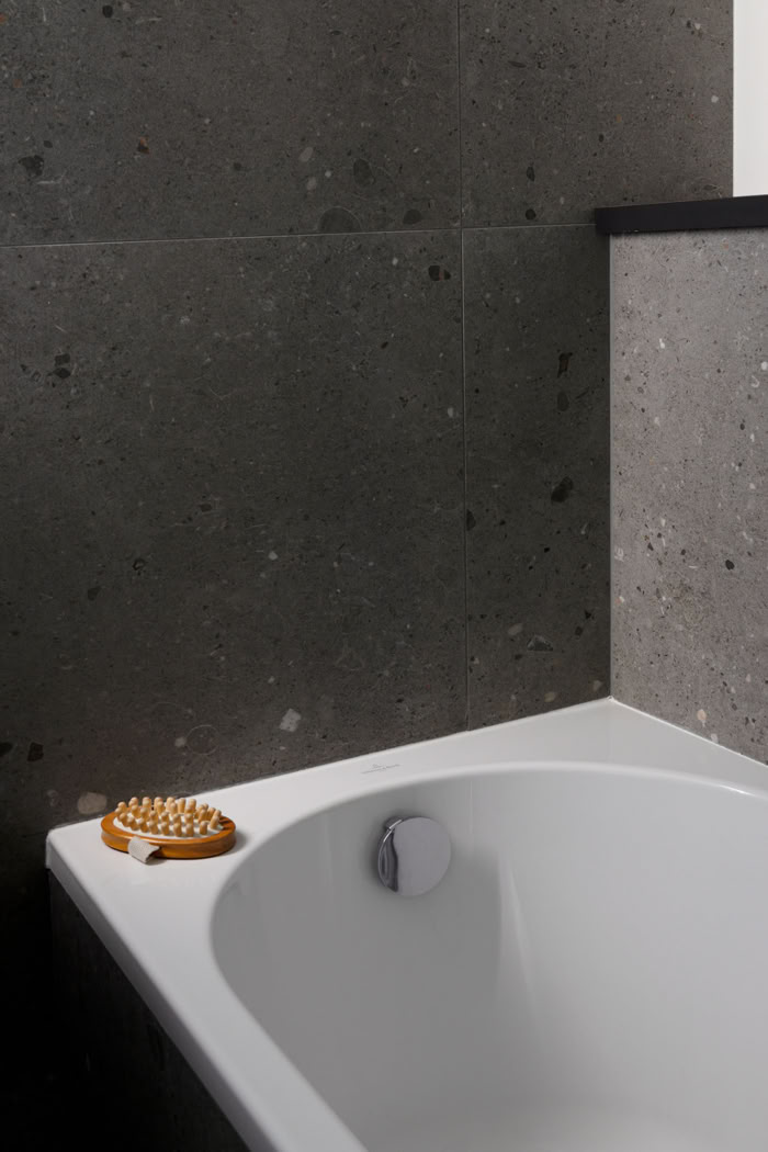 Détail baignoire blanche et revêtement carrelage gris, ambiance feutrée et pureté des lignes en Moselle.